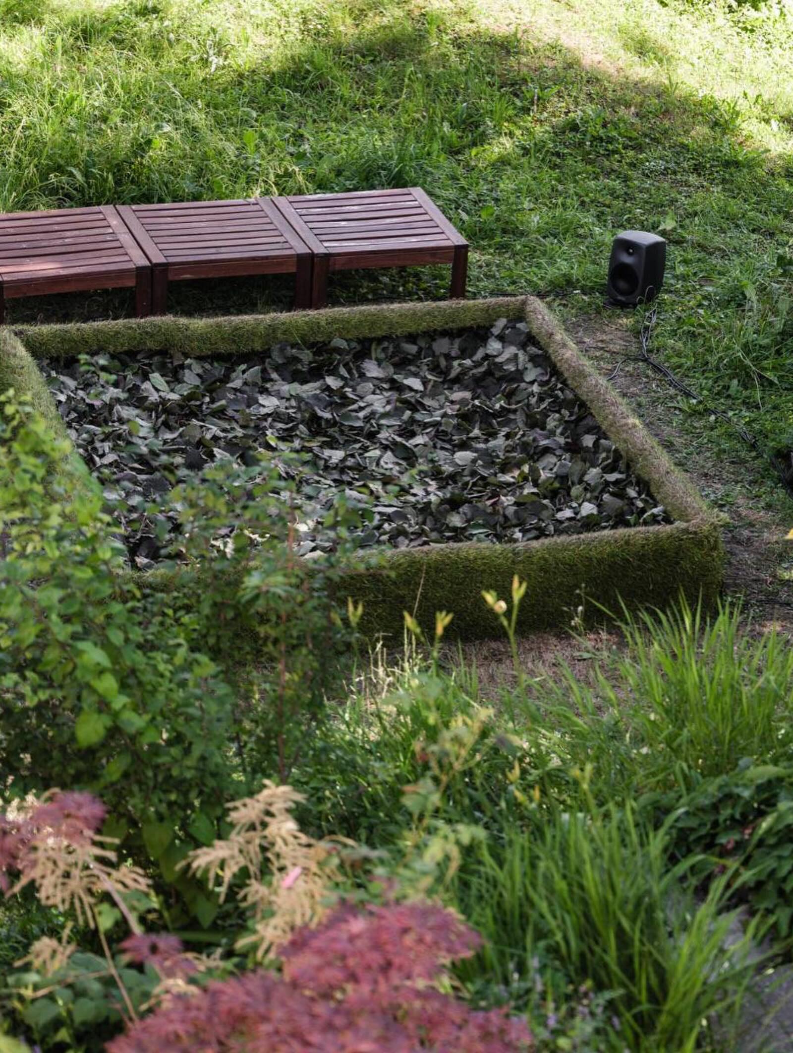 The leaf-filled bed framed by moss and flowering plants